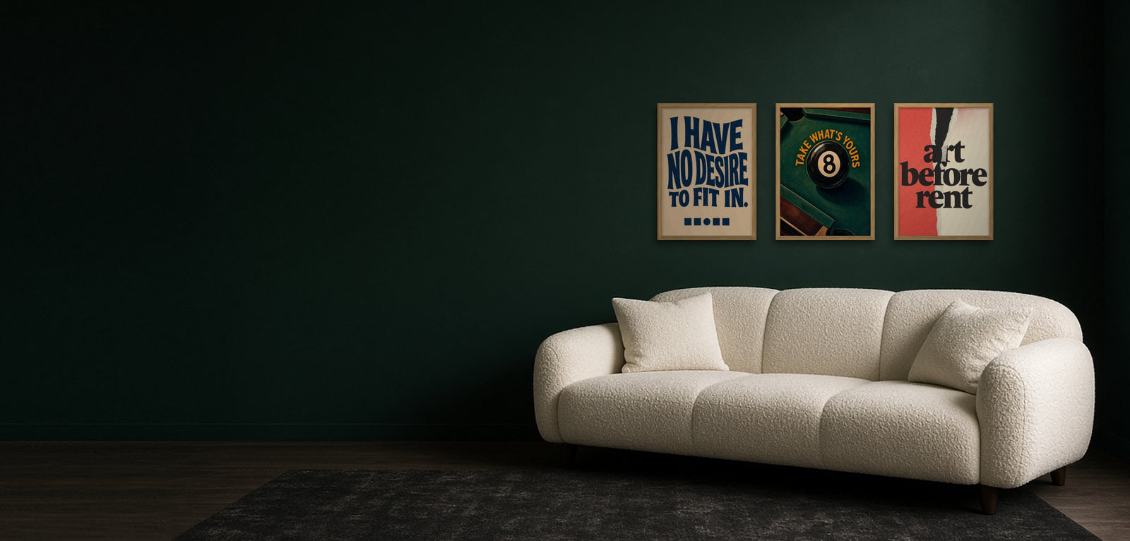 I Have No Desire To Fit In, Take What's Yours and Art Before Rent in oak frames on a dark green wall, above a cream bouclé sofa in a room lit by a TV